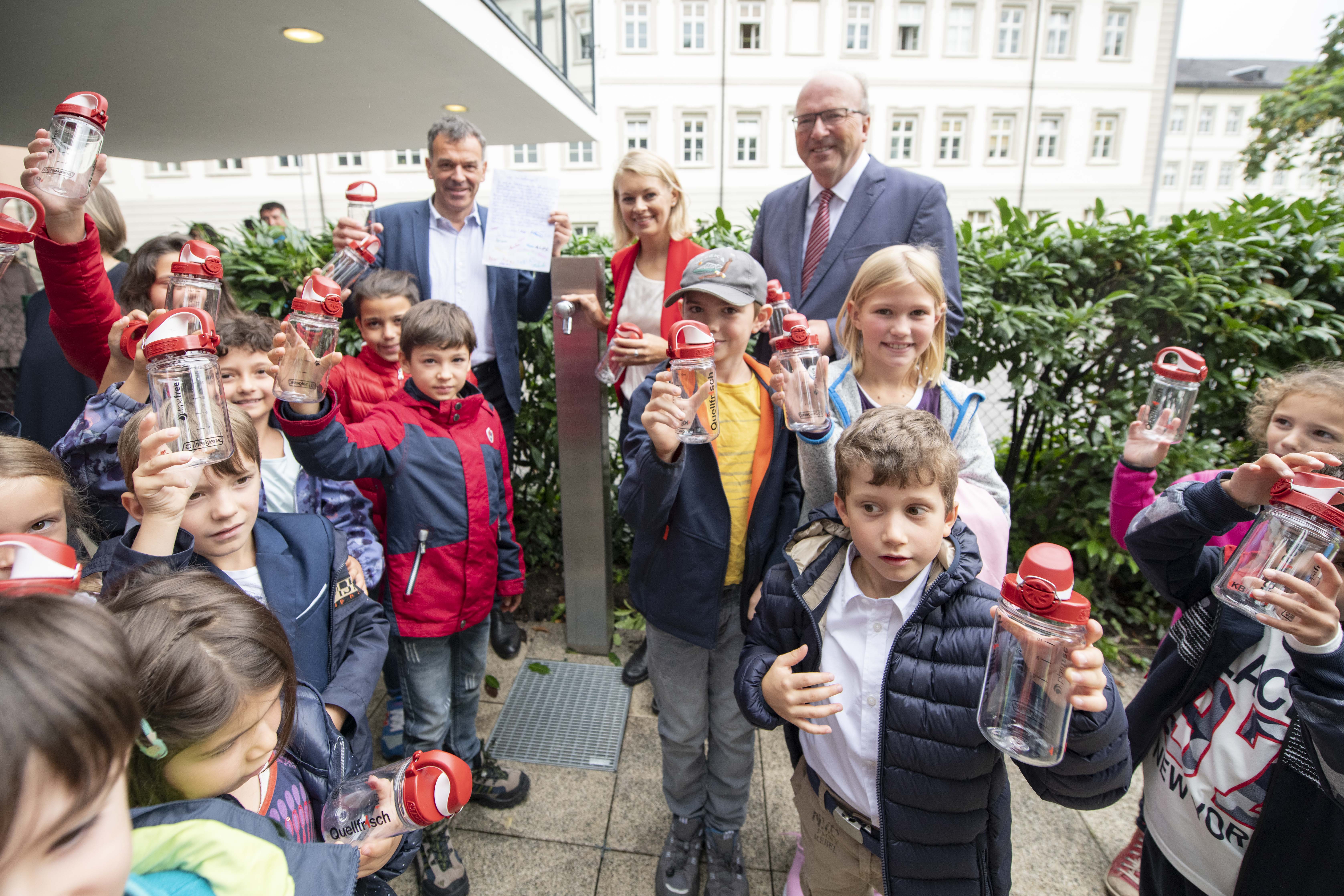 Die Schülerinnen und Schüler der Volksschule Innere Stadt freuen sich mit Bürgermeister Georg Willi, Stadträtin Elisabeth Mayr und IKB-Vorstandsvorsitzenden Helmuth Müller (r.) über die neuen Trinkflaschen.