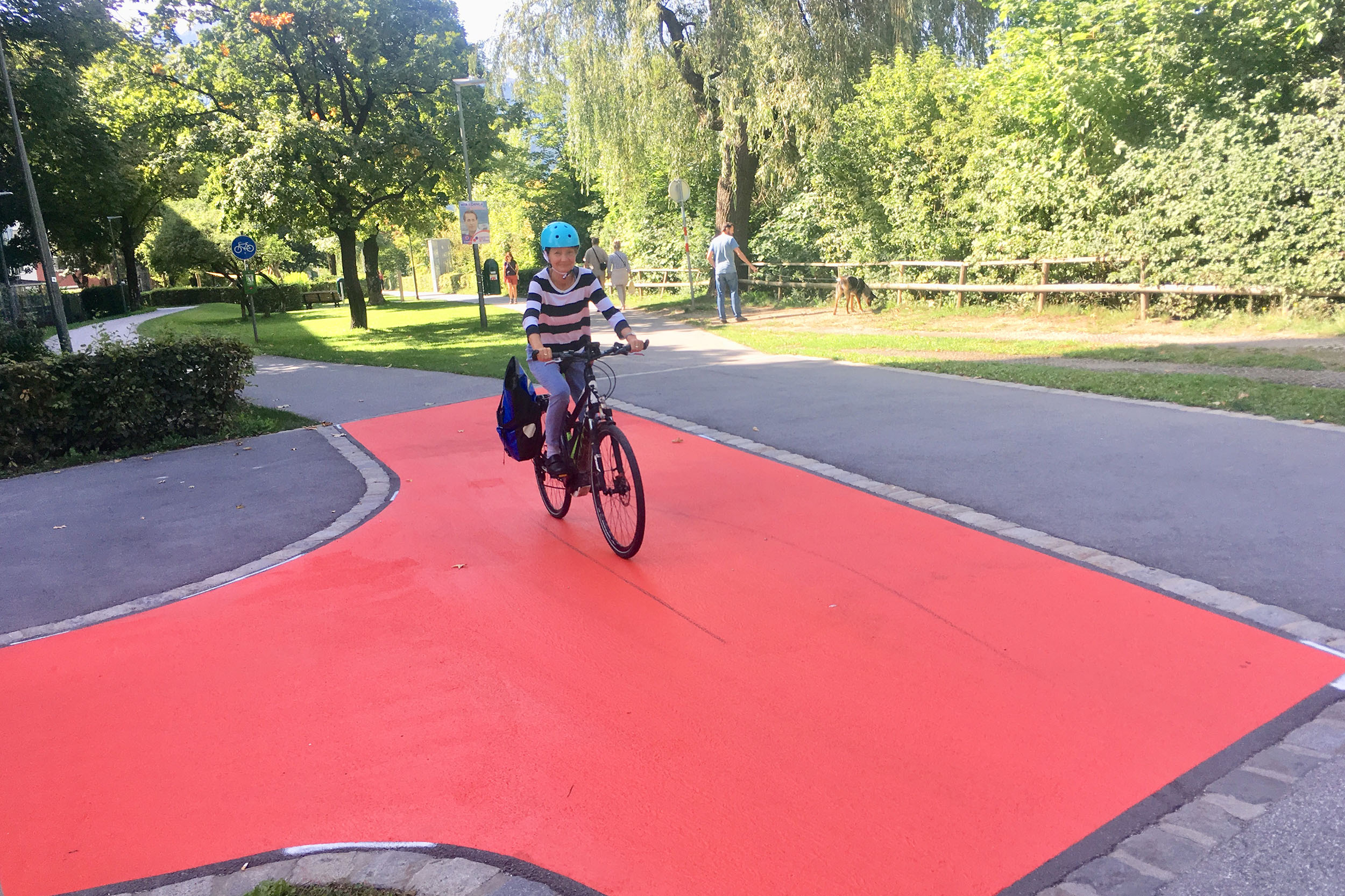 Mobilitätsstadträtin Uschi Schwarzl fährt auf dem roten Teppich Probe, der zu erhöhter Vorsicht zwischen den VerkehrsteilnehmerInnen sorgen soll.