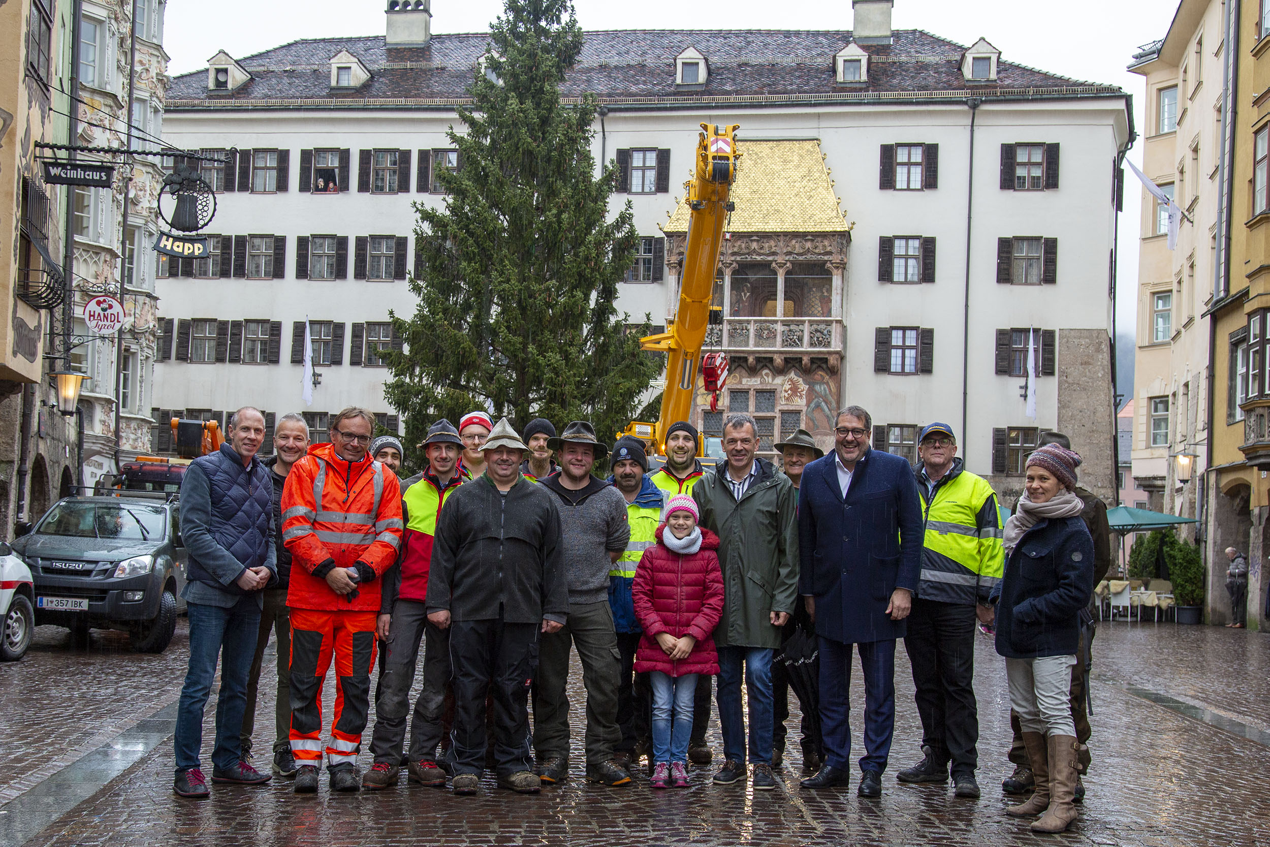 Bürgermeister Georg Willi (6.v.r.) und Vizebürgermeister Franz X. Gruber (4.v.r.) gratulieren mit Robert Neuner (Geschäftsführer IAI Veranstaltungs GmbH; 2.v.l.) und Bernhard Vettorazzi (Geschäftsführer Stadtmarketing Innsbruck; links) dem Team vom städtischen Forstamt zur erfolgreichen Aufstellung des Christbaums vor dem Goldenen Dachl.