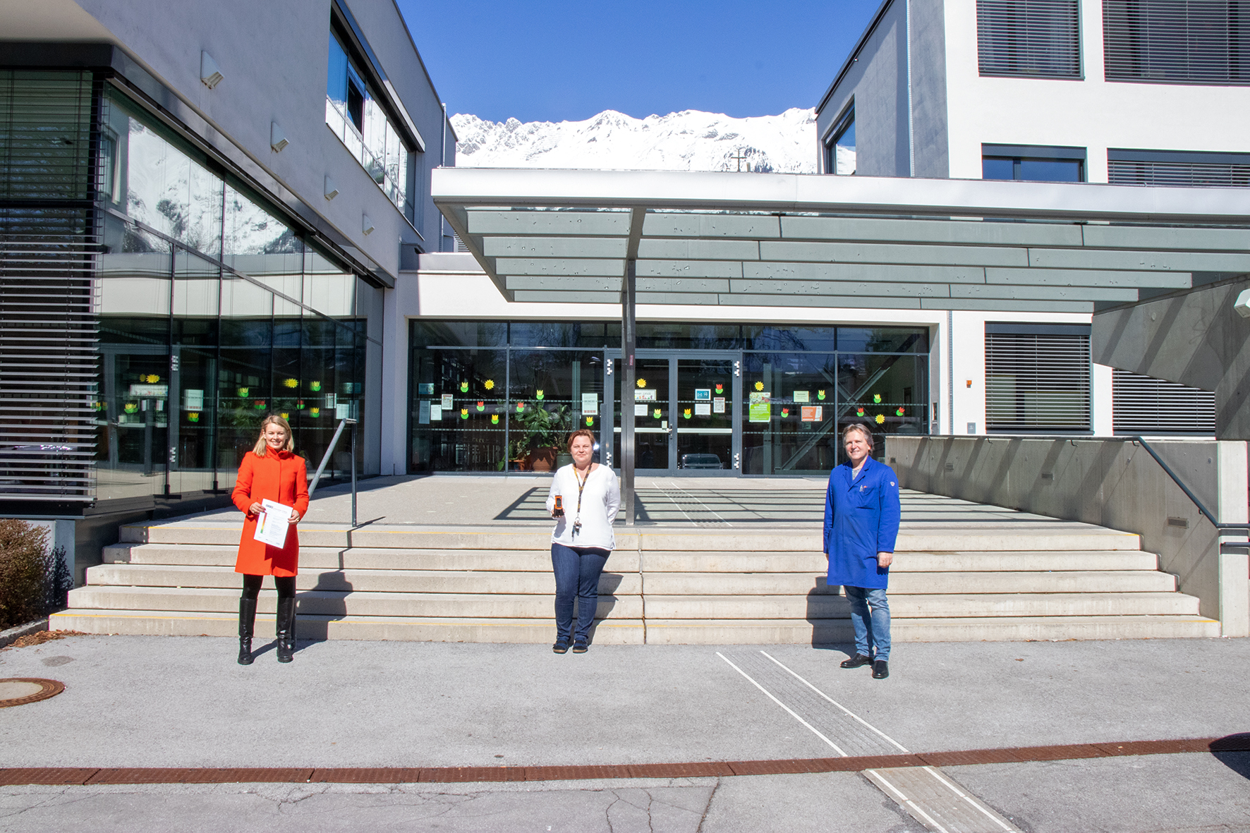 Stadträtin Elisabeth Mayr, Direktorin Ursula Masetti und Schulwart Dietmar Carli mit dem neuen CO2-Messgerät vor der Volksschule Reichenau.