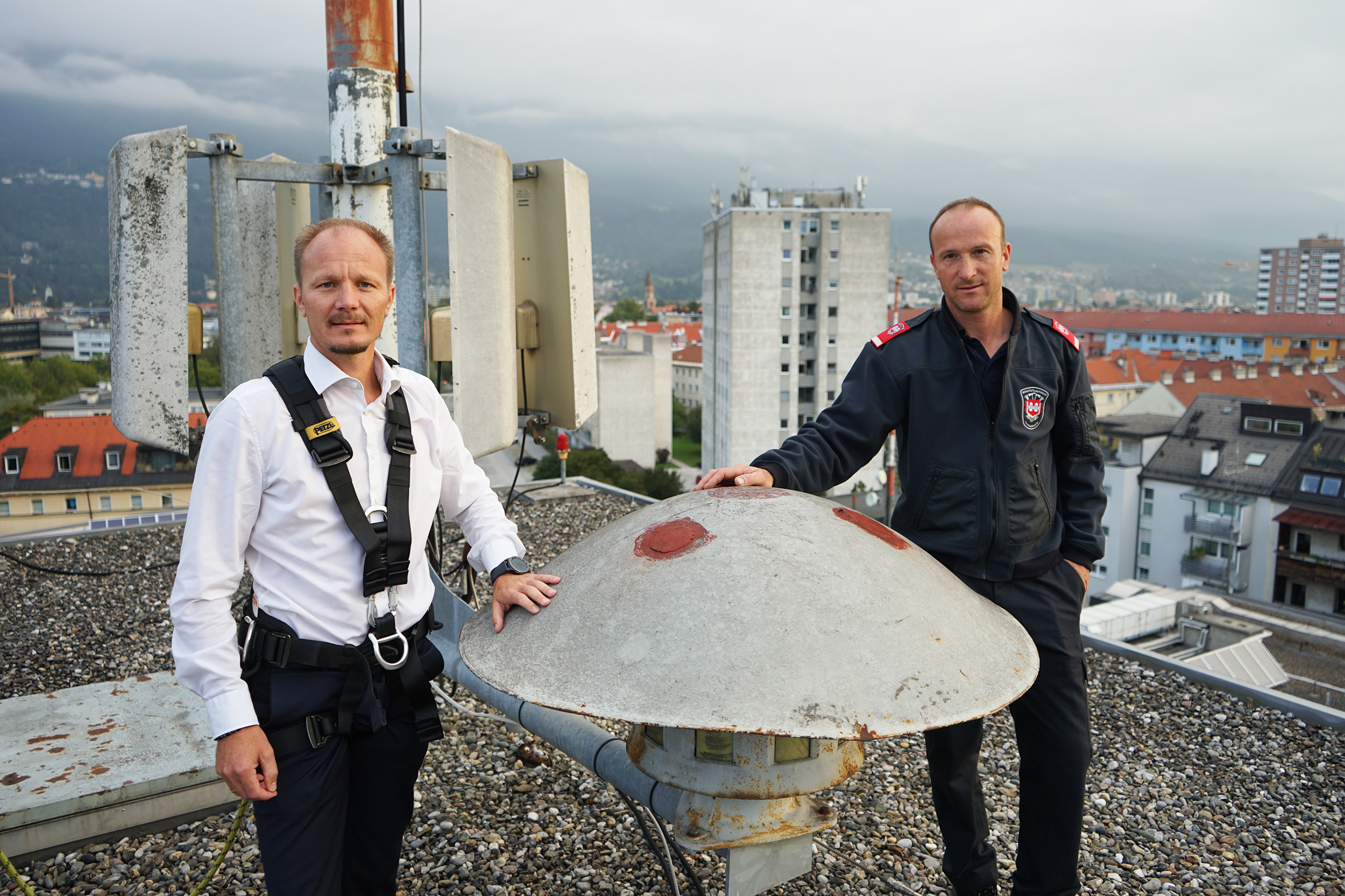 Vizebürgermeister Johannes Anzengruber und Roland Alessandri von der Berufsfeuerwehr inspizieren die Sirene am Dach der Hauptfeuerwache in Pradl.
