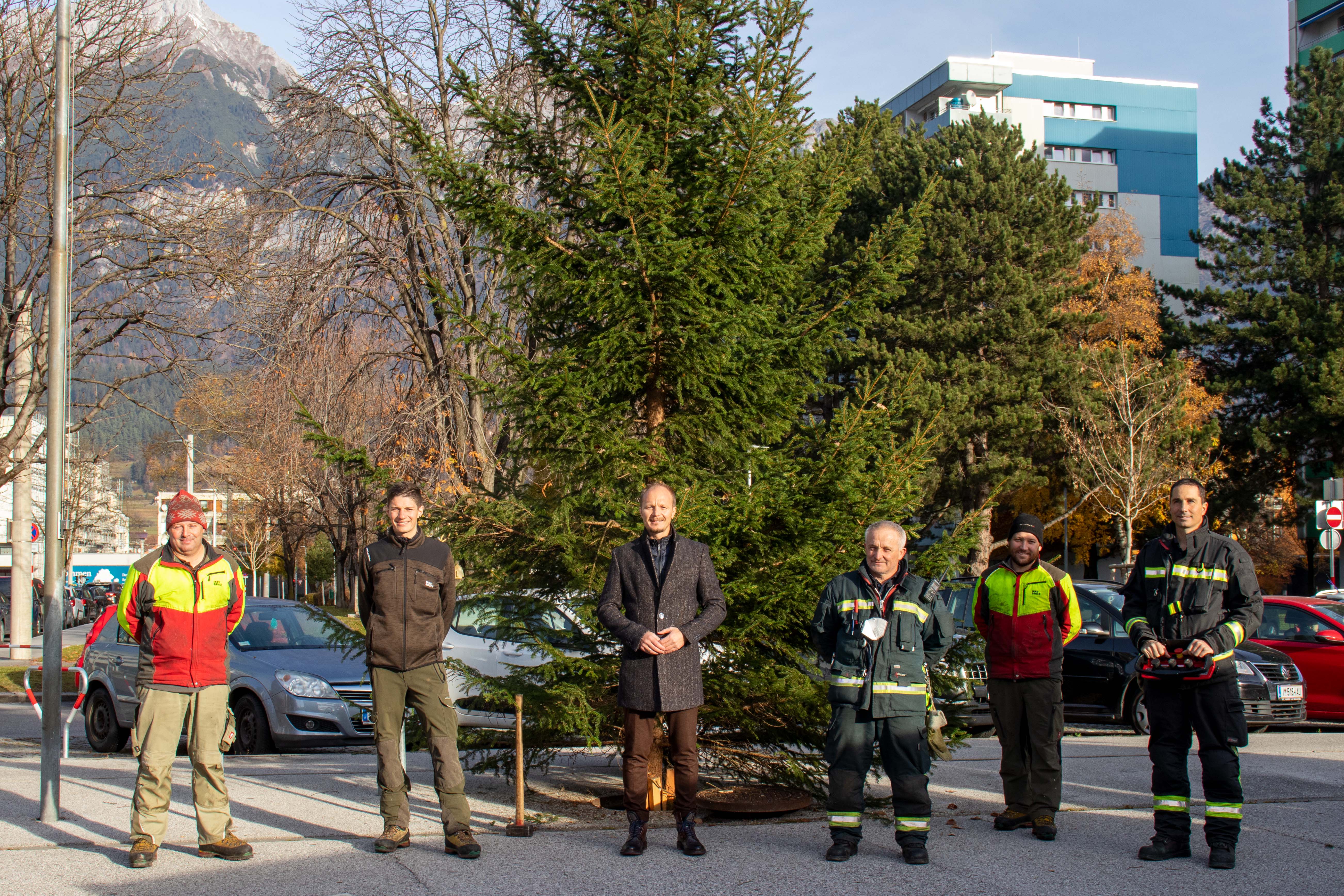 Abschließend wurde nun auch im Stadtteil Olympisches Dorf ein Christbaum aufgestellt. Vizebürgermeister Anzengruber (3.v.l.) und Förster Florian Jäger (2.v.l.) freuen sich gemeinsam mit den Mitarbeitern der Berufsfeuerwehr Innsbruck und des Amtes für Wald und Natur über die mehr als 220 Bäume im Stadtgebiet.