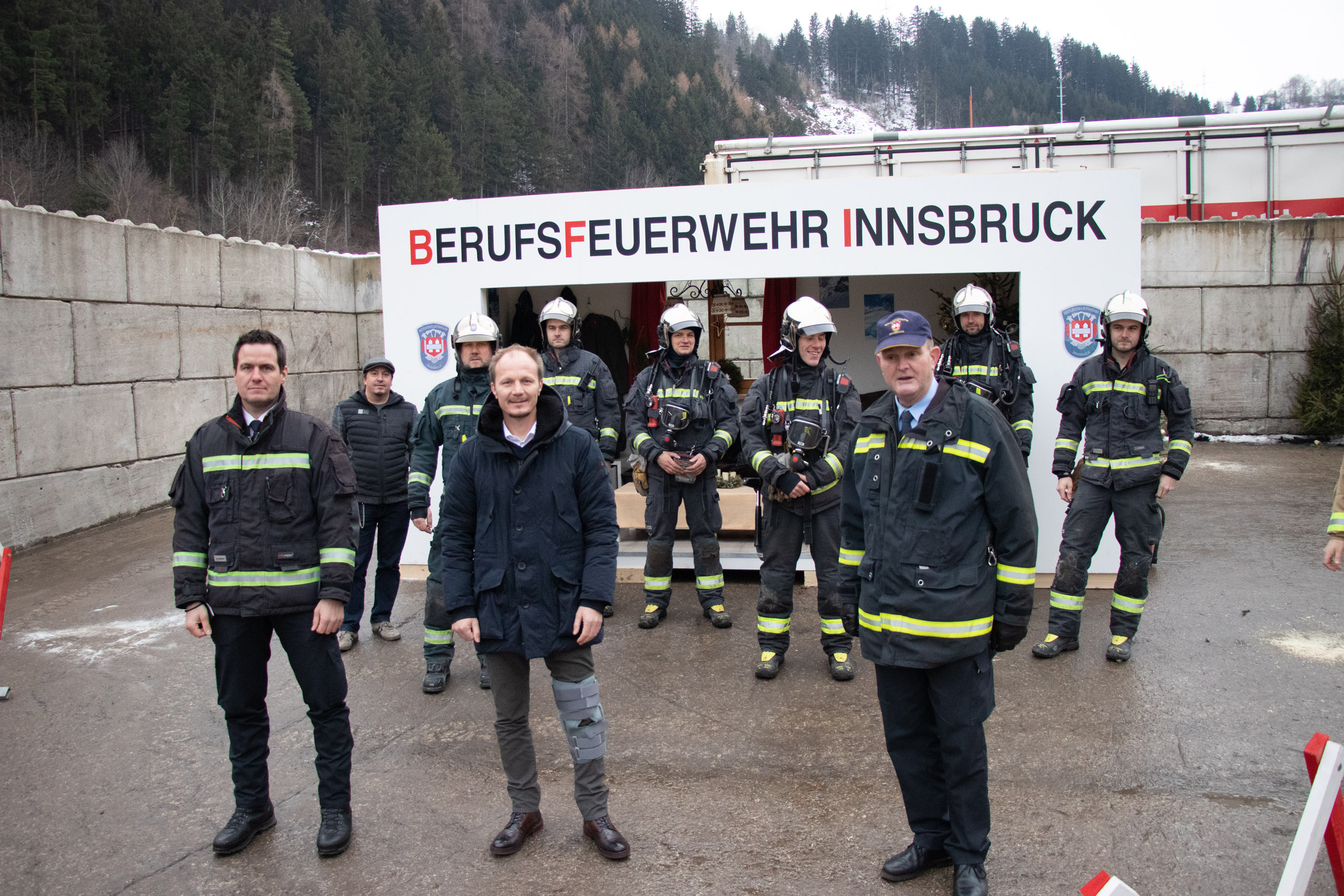 Branddirektor Helmut Hager (links), Vizebürgermeister Johannes Anzengruber, Branddirektor-Stv. Johann Zimmermann und die Löschgruppe der Berufsfeuerwehr vor dem  Übungsszenario, das die Folgen eines Christbaumbrandes vor Augen führt.