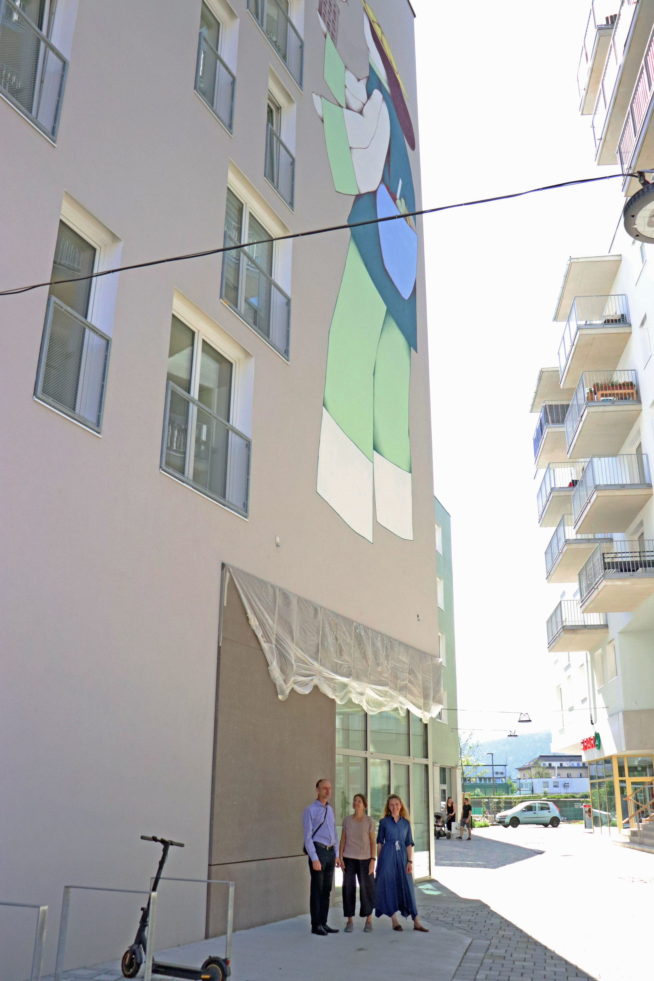 Zwischenstand beim Mural in der Campagne Reichenau: IIG Projektleiter Martin Franzmair, Stadträtin Uschi Schwarzl und Kulturamtsleiterin Isabelle Brandauer sind von der Dimension und der Qualität des Wandbildes von RUIN begeistert.