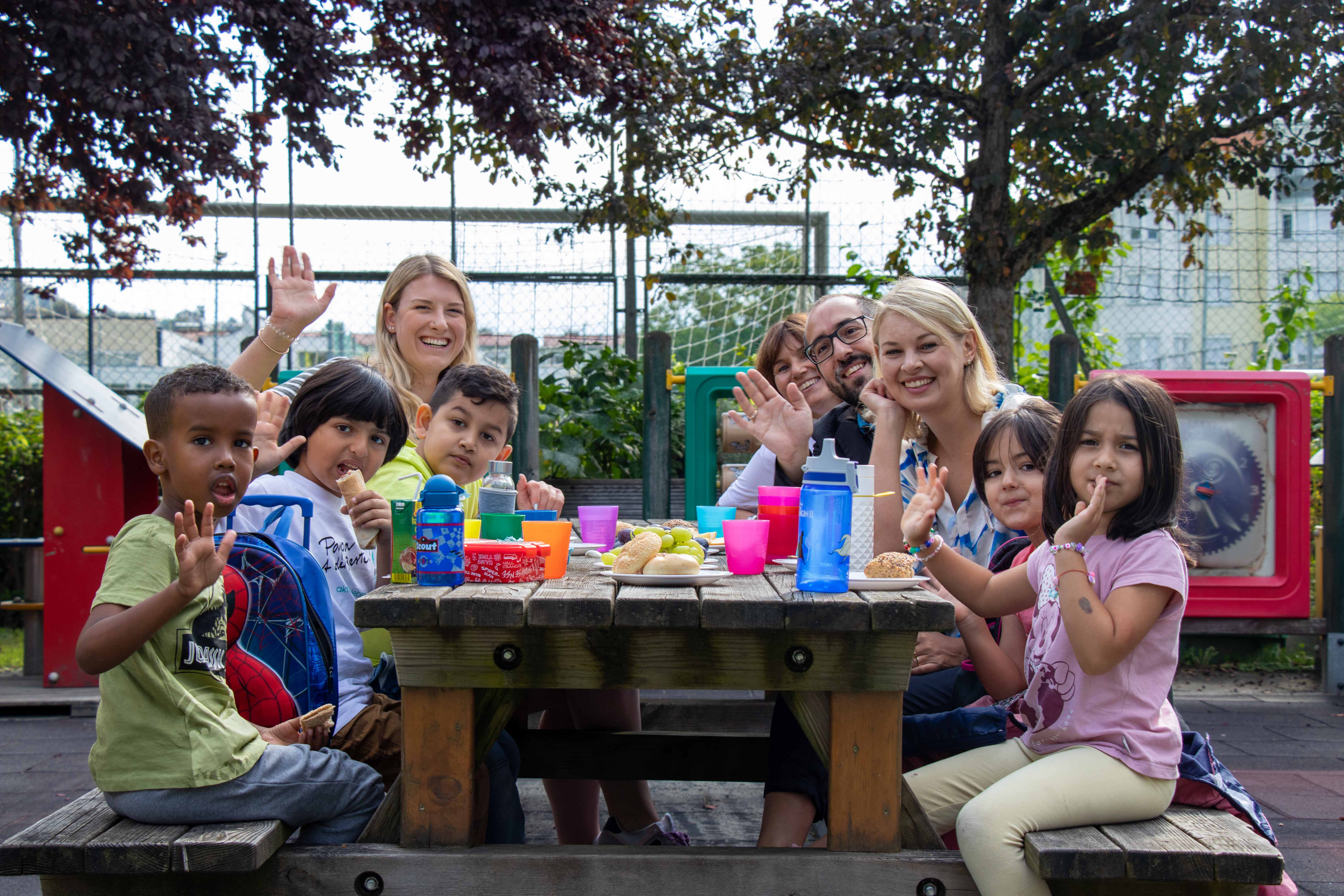 (v. l. ) Pädagogin Julia Untertroger, Nicola Köfler (Amt für Stadtplanung, Stadtentwicklung und Integration), Projektleiter Jugendrotkreuz Alexander Sulzenbacher-Schell und Stadträtin Elisabeth Mayr jausnen gemeinsam mit den Kindern.