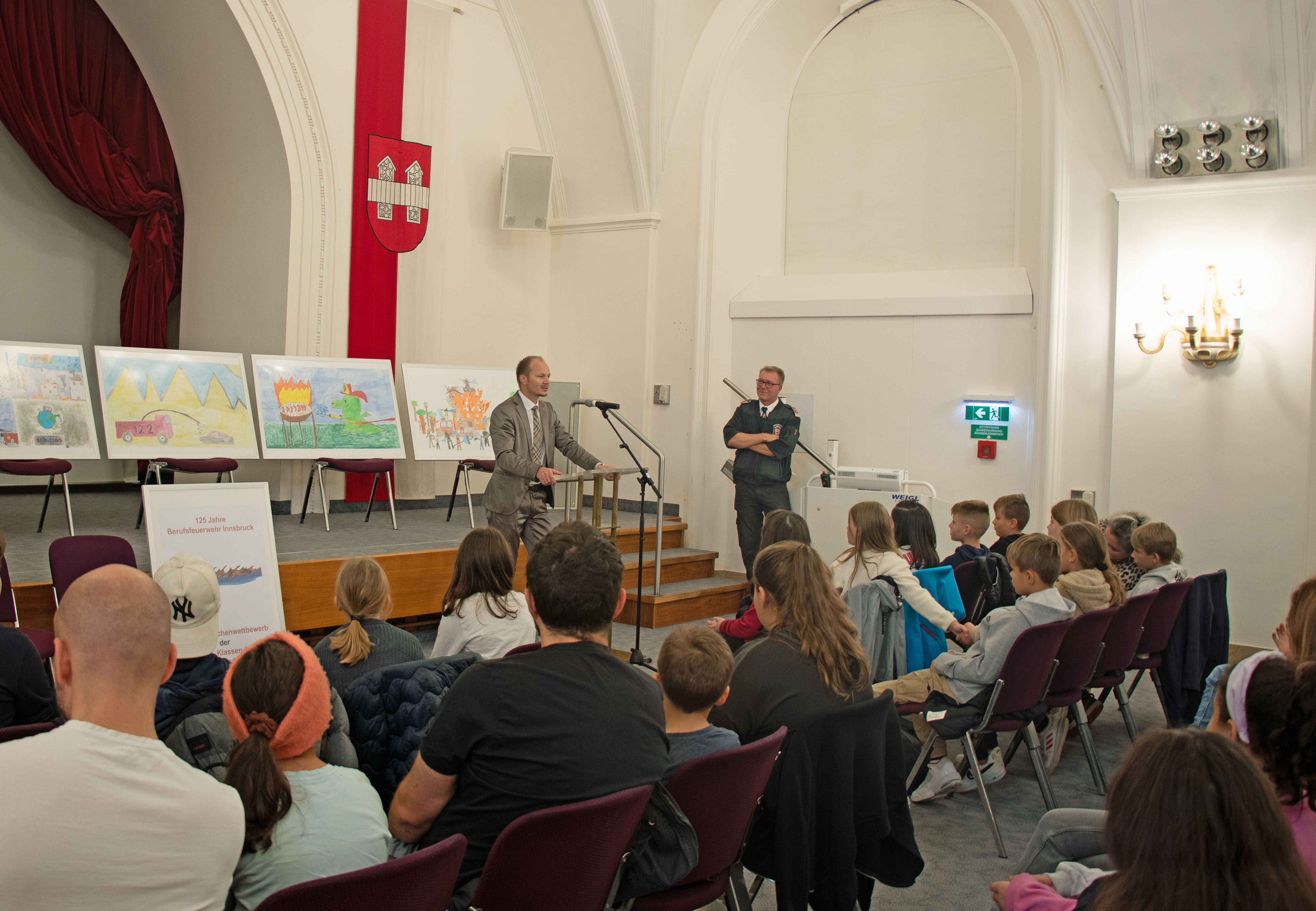 Der für Sicherheit zuständige Vizebürgermeister Johannes Anzengruber wendet sich bei der Preisverleihung an das junge Publikum im vollbesetzten Ursulinensaal.