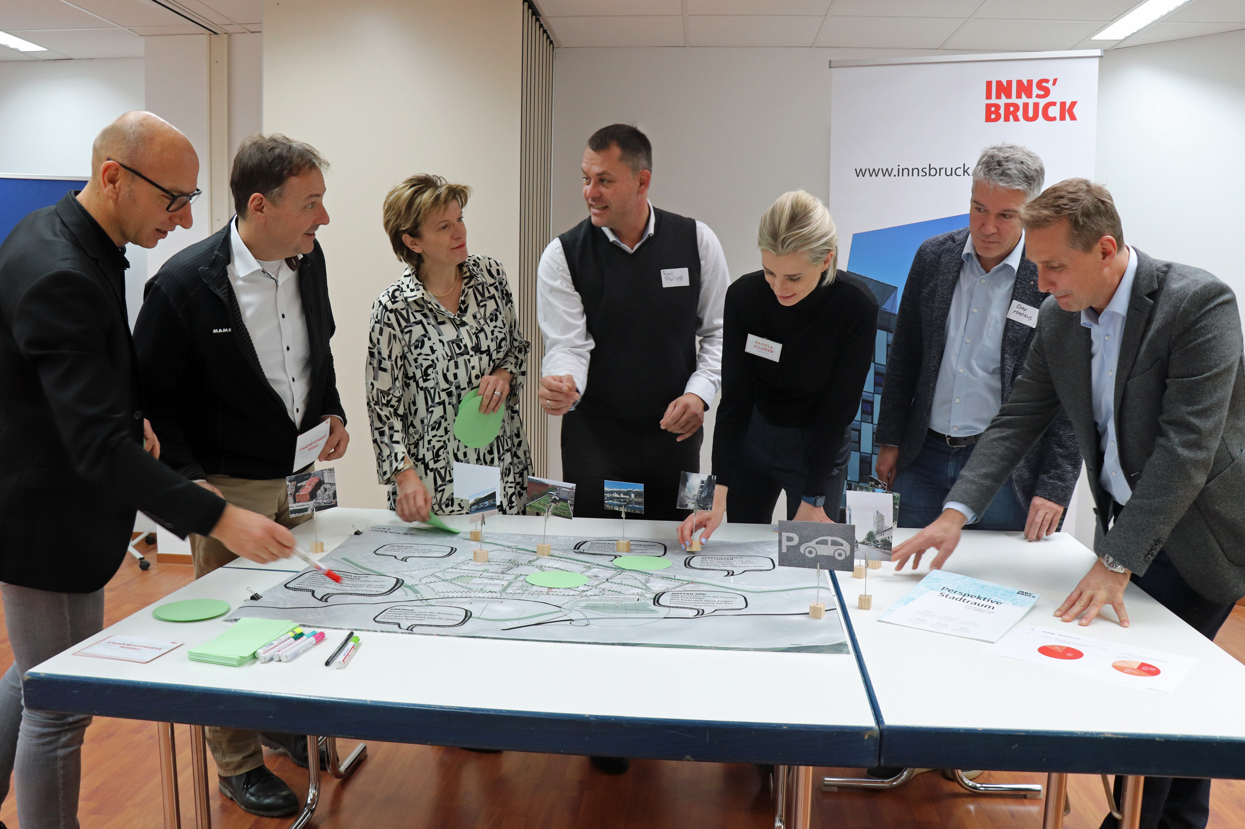 Wolfgang Andexlinger (Stadtplanung, Stadtentwicklung und Integration), Gerhard Hofer (Immobilien, Wirtschaft und Tourismus), Stadträtin Christine Oppitz-Plörer, Philipp Resl (Businesspark Innsbruck), Daniela Allmeier (Raumposition), Markus Dax (GF STEKA Werke, Wirtschaftskammer-Bezirksausschuss Innsbruck-Stadt und Sprecher der Rossau) und Franz Jirka (Bezirksstellenobmann WK Tirol; v.l.n.r.) an einem der vier Themen-Planungstische.