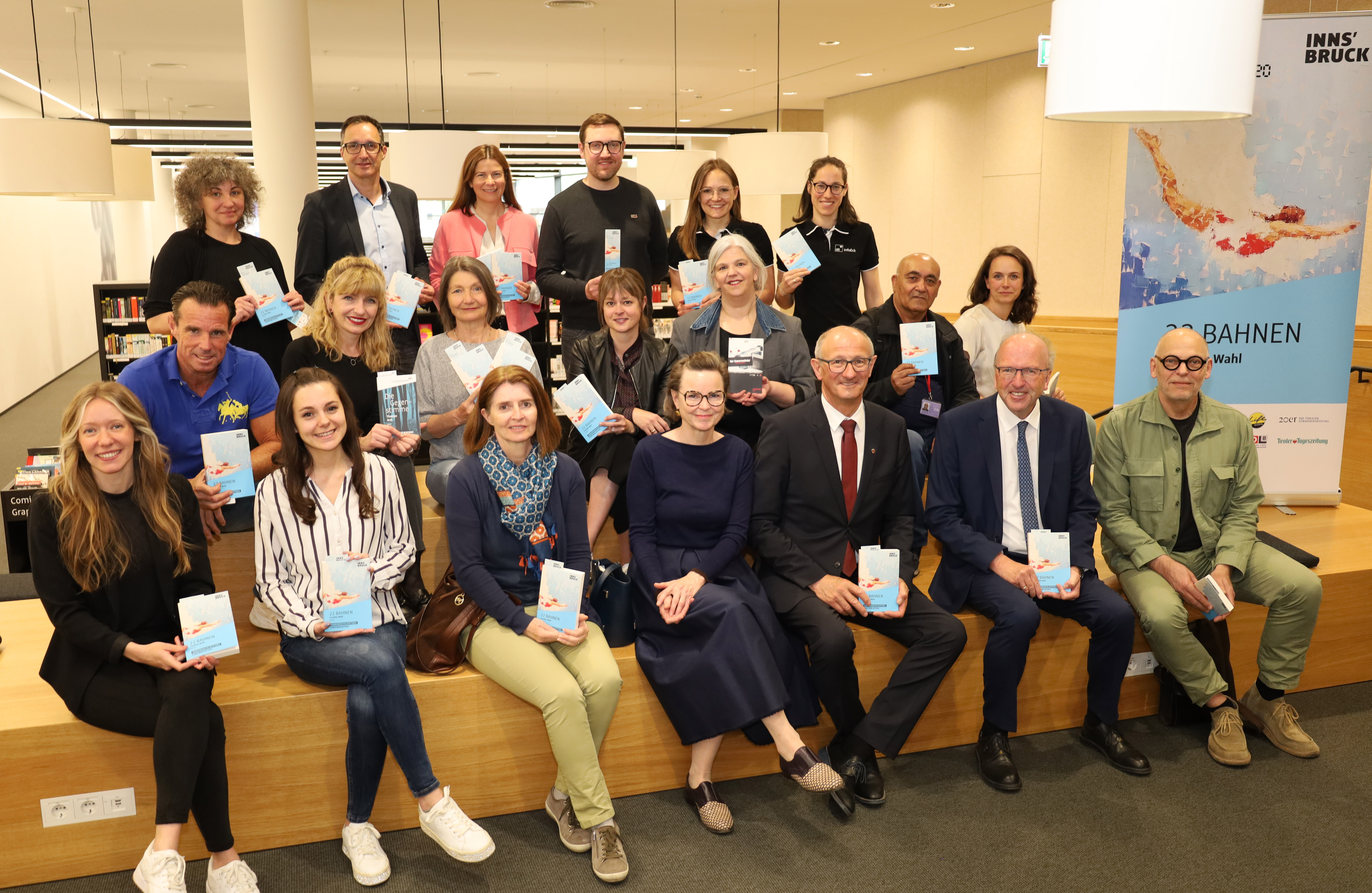 Die Leseaktion "Innsbruck liest" feiert heuer 20 Jahre: Landeshauptmann Anton Mattle (1. Reihe, 3. v.r.), Kulturstadträtin Uschi Schwarzl (2. Reihe, 3. v.l.), Juryvorsitzende Doris Eibl (1. Reihe, Mitte), die VeranstalterInnen und SponsorInnen freuen sich auf das Buch "22 Bahnen" von Caroline Wahl.