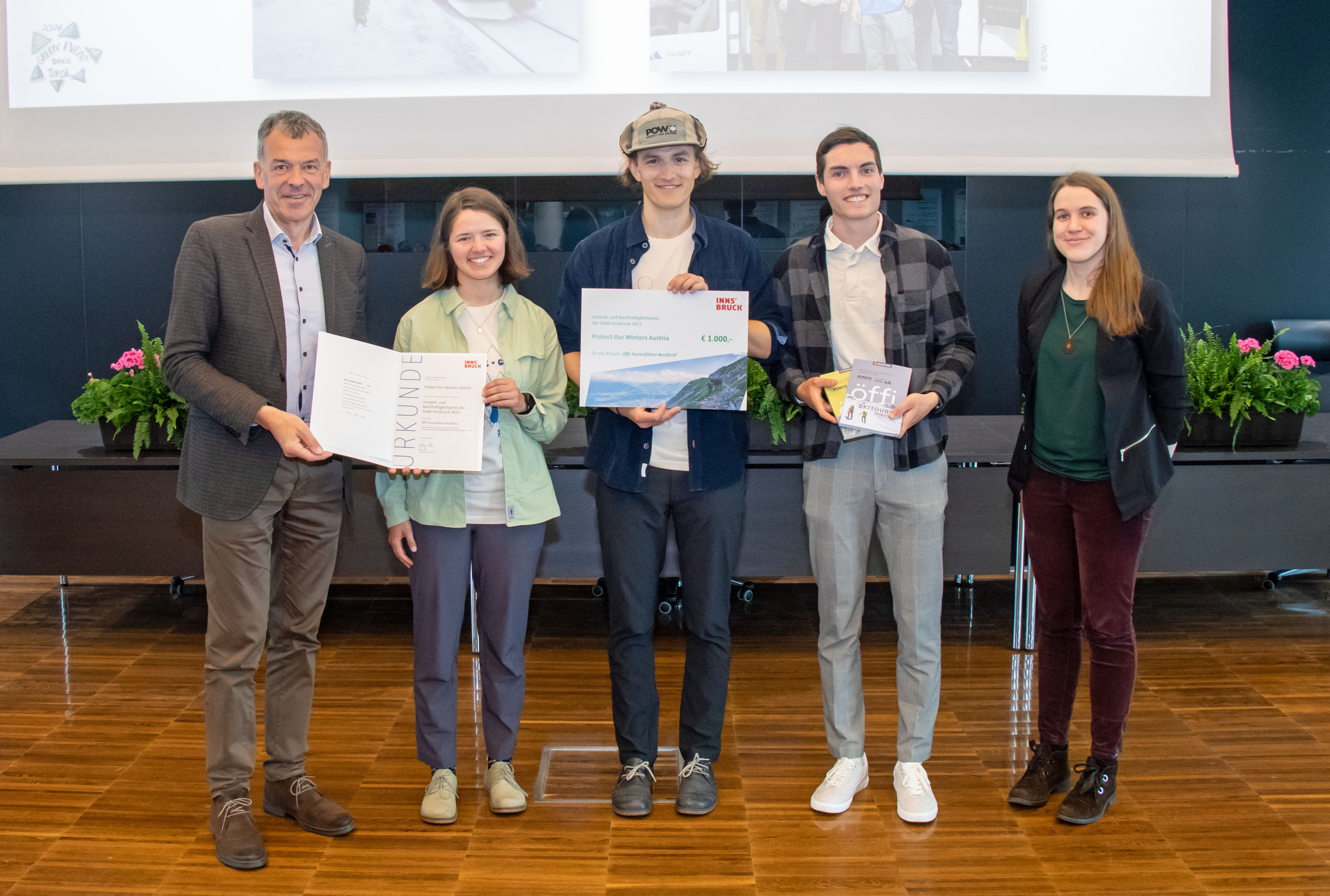 Bürgermeister Georg Willi (l.) und Nadine Winzer vom Amt Klimaneutrale Stadt (r.) freuen sich mit den VertreterInnen von "Protect Our Winters Austria" über die Auszeichnung