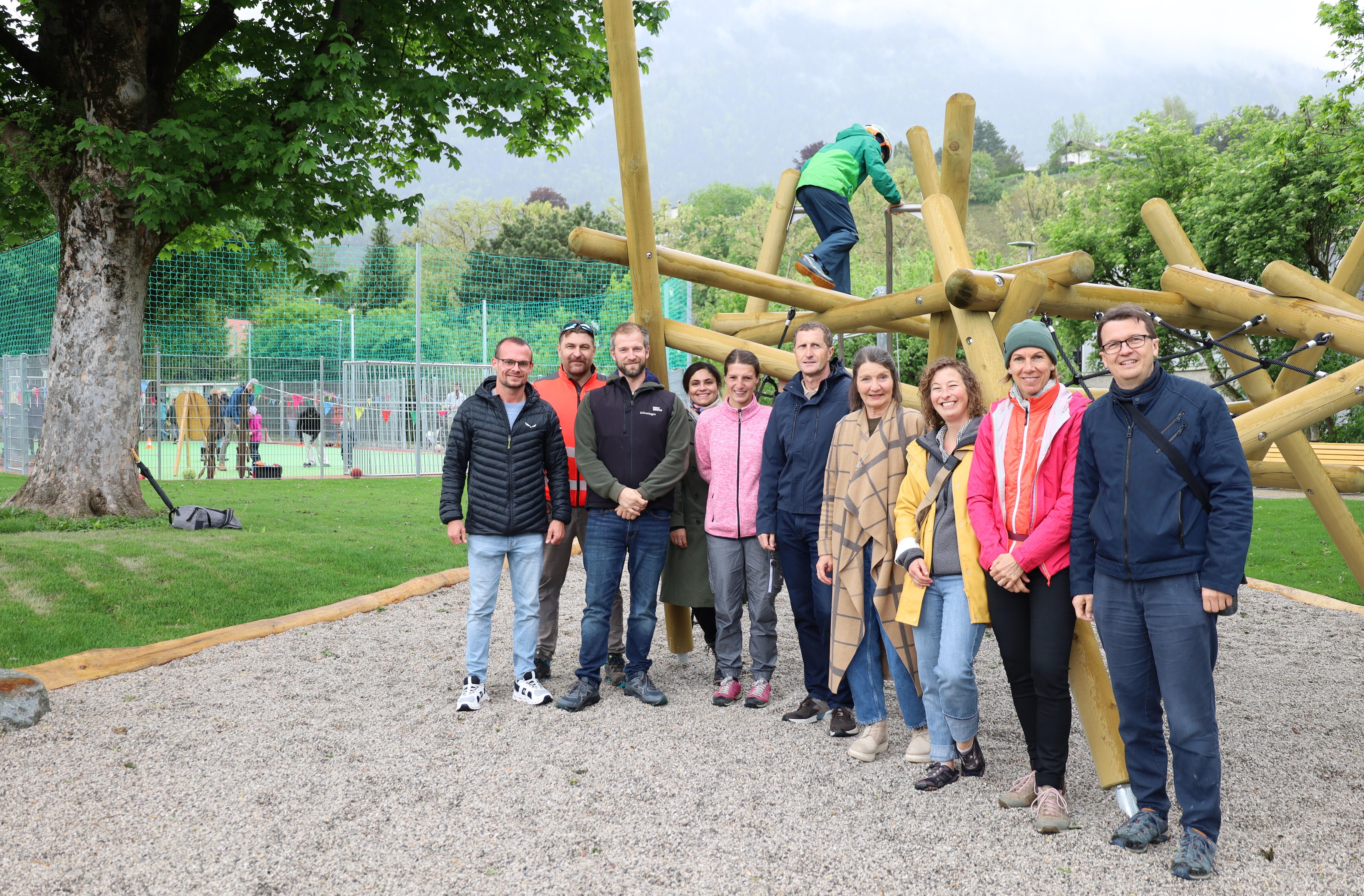 Große Freude anlässlich der Eröffnung des Ursulinenparks: Stadträtin Uschi Schwarzl (4. v.r.), Amtsvorstand Thomas Klingler (Mitte) mit seinem Team vom Referat Grünanlagen – Planung und Bau und Patricia Klahn (ISD-Stadtteilkoordinatorin Höttinger Au, 2. v.r.). Im Hintergrund der multifunktionale Ballspielplatz, der – wie auch das neue Klettergerüst – bereits eifrig ausprobiert wurde.