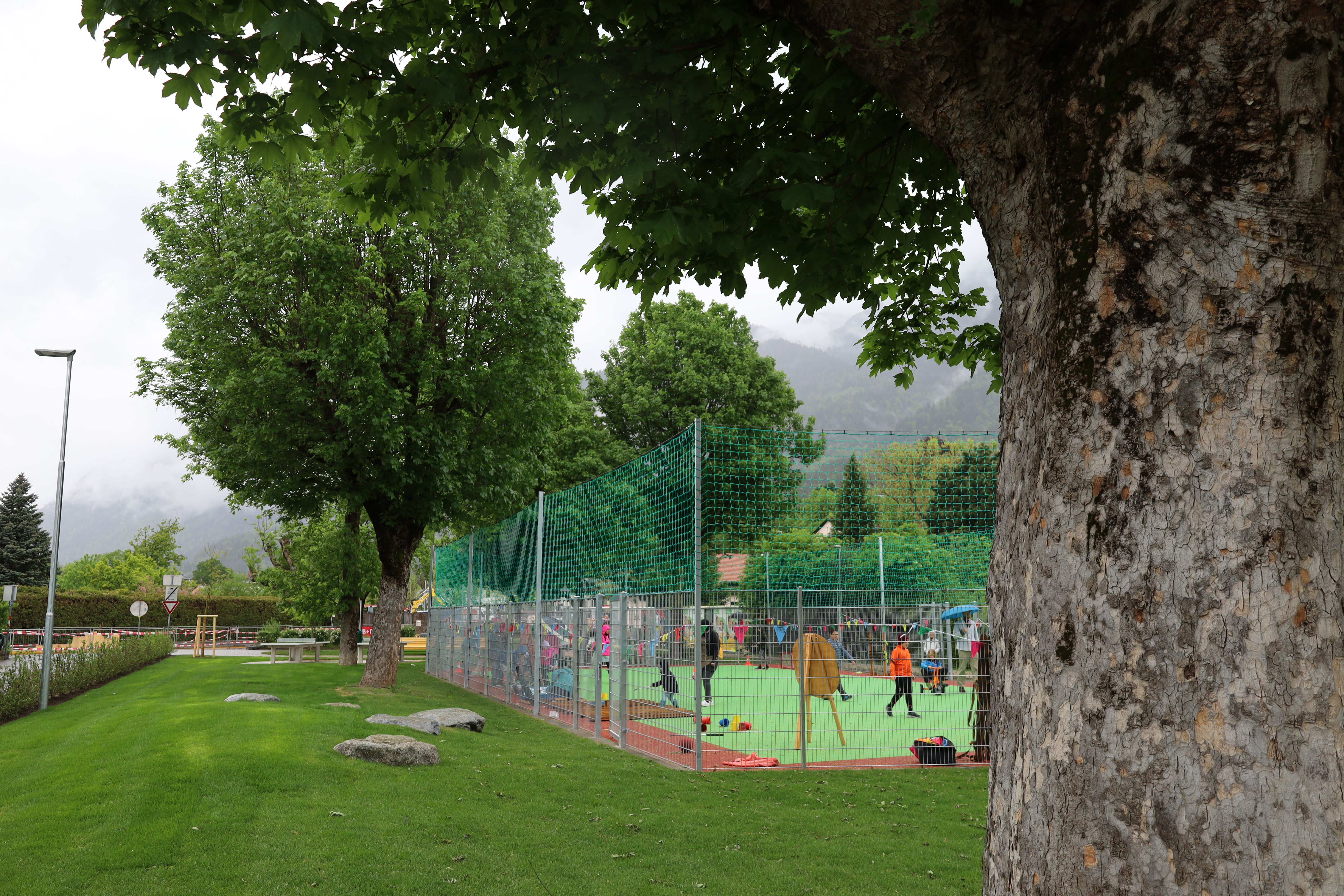 Der multifunktionale Ballspielplatz ist umgeben von schattenspendendem Baumbestand.