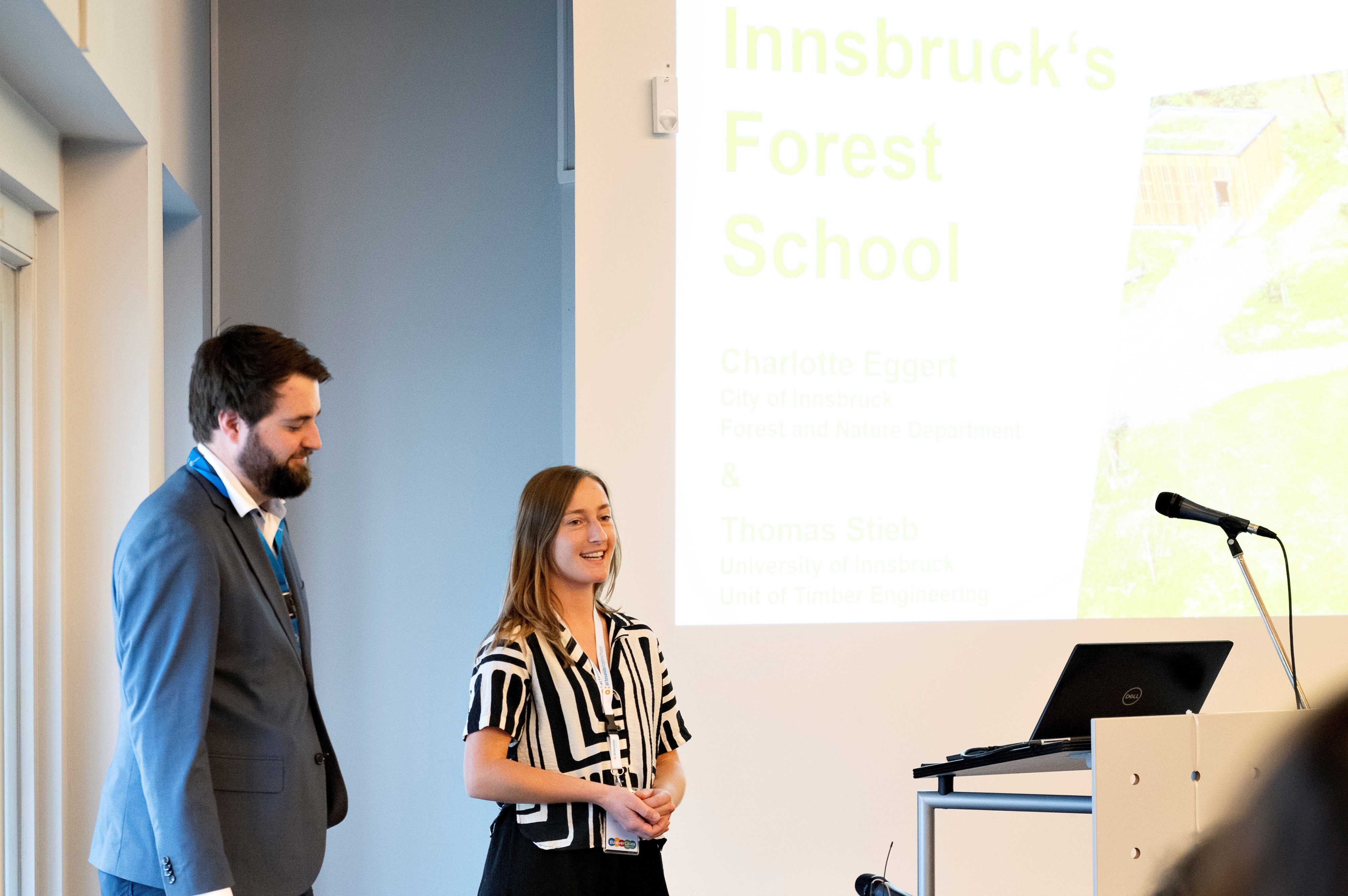 Die Stadt Innsbruck ist gemeinsam mit der Universität Innsbruck seit 2018 teil des EUniverCities-Netzwerks. Im Rahmen eines Treffens Anfang Mai in Ghent wurden die teilnehmenden Städte gebeten, Best Practice-Beispiele zu präsentieren. Aus Innsbrucker Sicht wurde die Waldschule von Charlotte Eggert (r., Referat Natur und Erholung) und Thomas Stieb (Universität Innsbruck, Institut für Konstruktion und Materialwissenschaften, AB Holzbau) vorgestellt. Dort können Innsbrucks Pflichtschulen ihren SchülerInnen die Bedeutung des Waldes vermitteln und das Umweltbewusstsein stärken. Die Waldschule bietet eine einzigartige Lernumgebung, in der SchülerInnen die Wichtigkeit des Waldes erkennen und praktische Fähigkeiten erwerben können, um aktiv zum Schutz und zur nachhaltigen Nutzung des Waldes beizutragen.