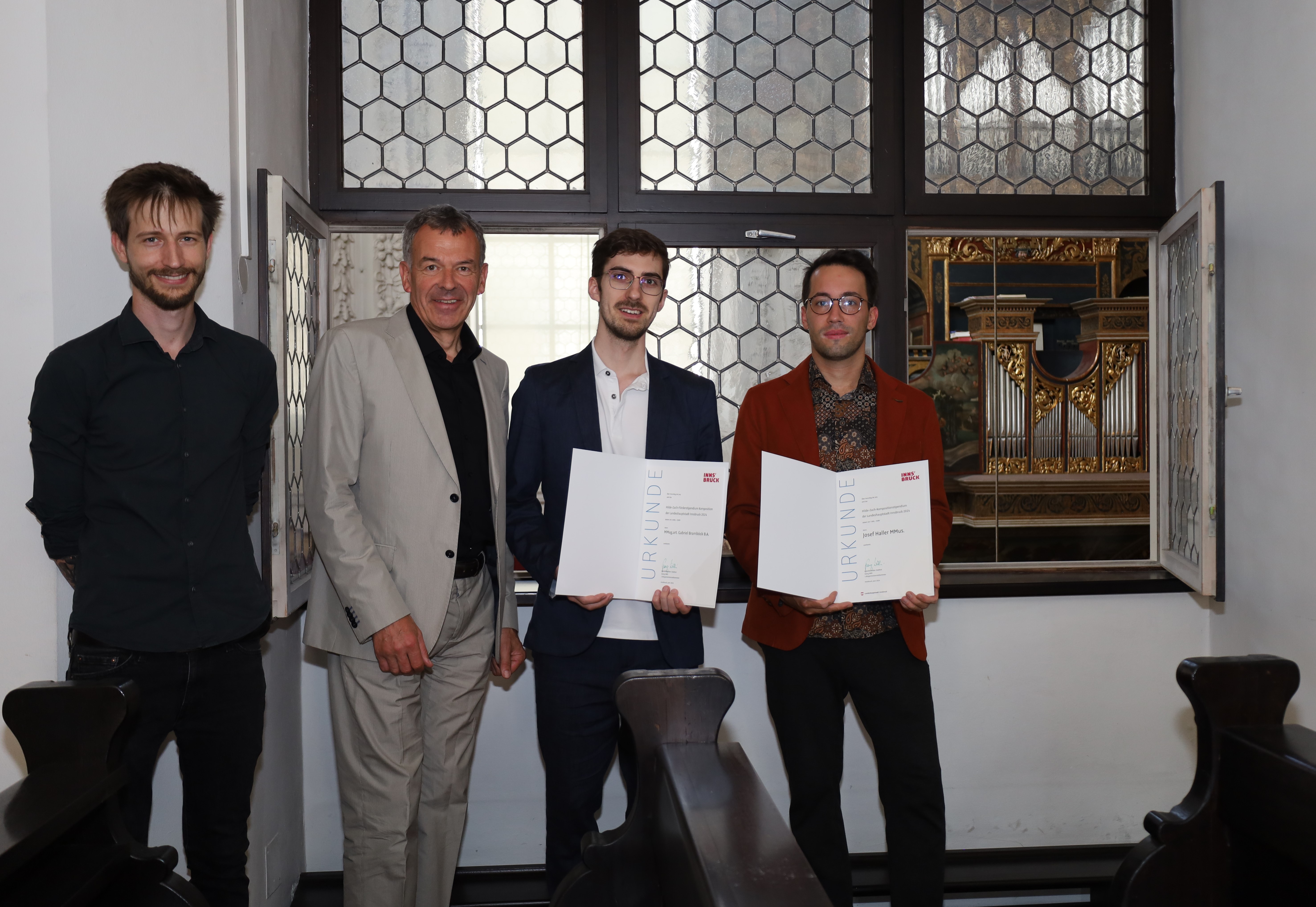 Die Preisträger Josef Haller (1. v.r.) und Gabriel Bramböck (2. v.r.) vor der Ebertorgel, der ältesten Orgel Österreichs (1558), in der Innsbrucker Hofkirche. Vizebürgermeister Georg Willi und Markus Margreiter (Kulturamt, 1. v.l.) gratulierten herzlich zum Hilde-Zach-Kompositionsstipendium 2024.