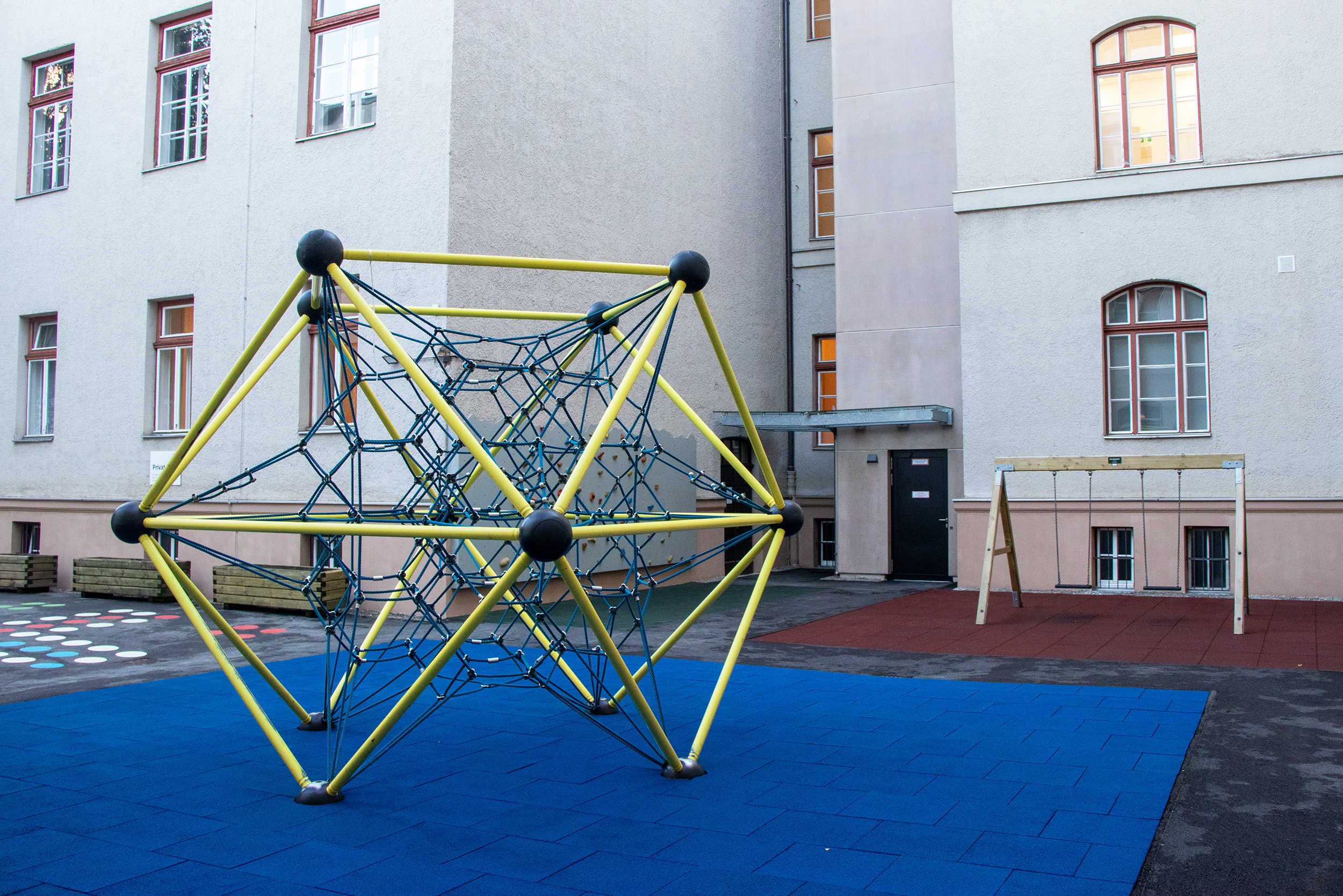 Der Spielbereich im Innenhof konnte ebenfalls saniert werden. Die neue Aufzugsanlage im Hintergrund fügt sich harmonisch in das denkmalgeschützte Umfeld ein und ermöglicht eine barrierefreie Zugänglichkeit.