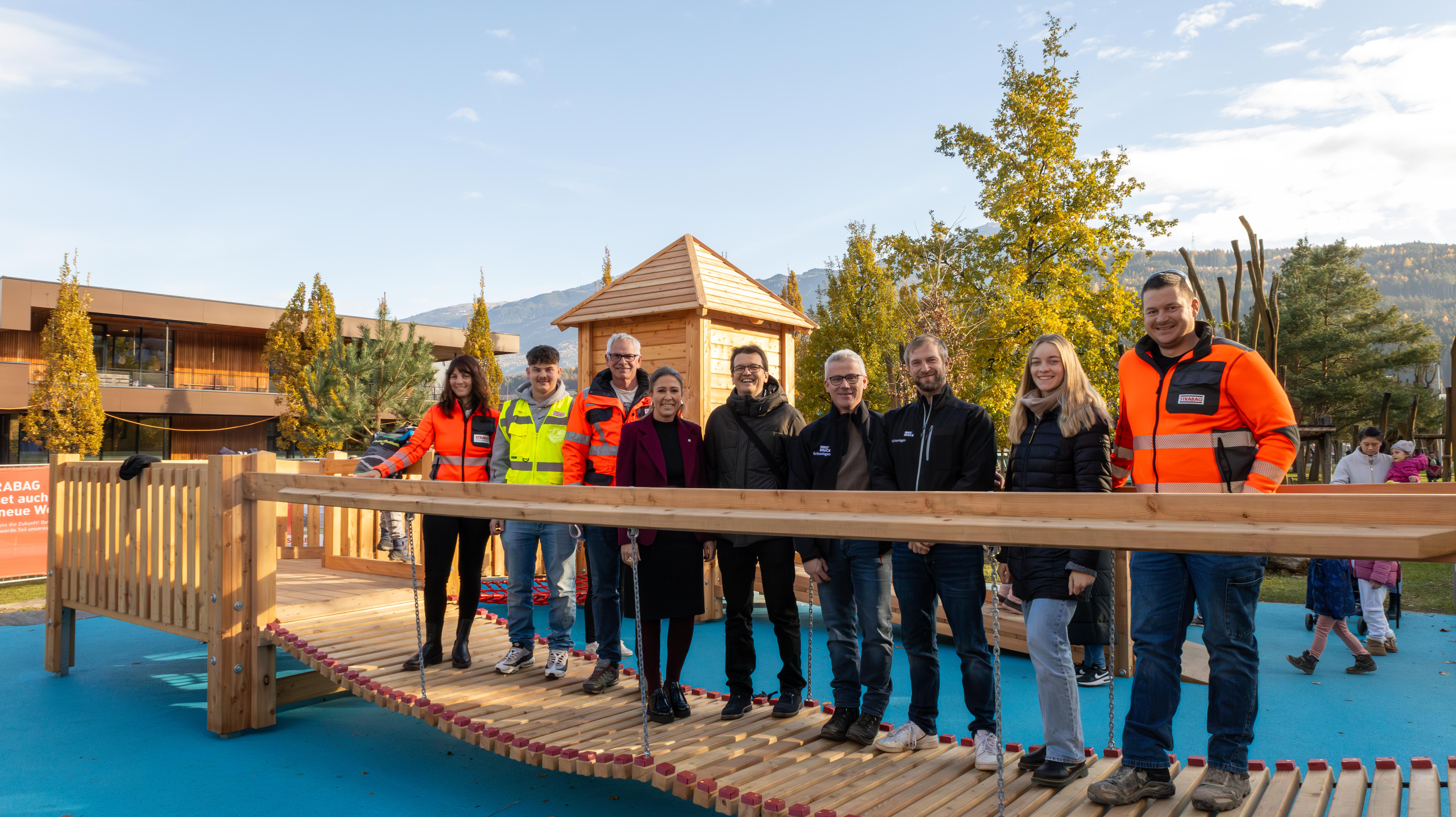 Stadträtin Mariella Lutz (4. v. l.), Referatseiter Markus Pinter (5. v. l., Grünanlagen – Planung und Bau) mit seinem Team sowie die Mitarbeitenden der Firma Strabag freuen sich über die gelungene Erweiterung des Spielplatzes Tivoli.