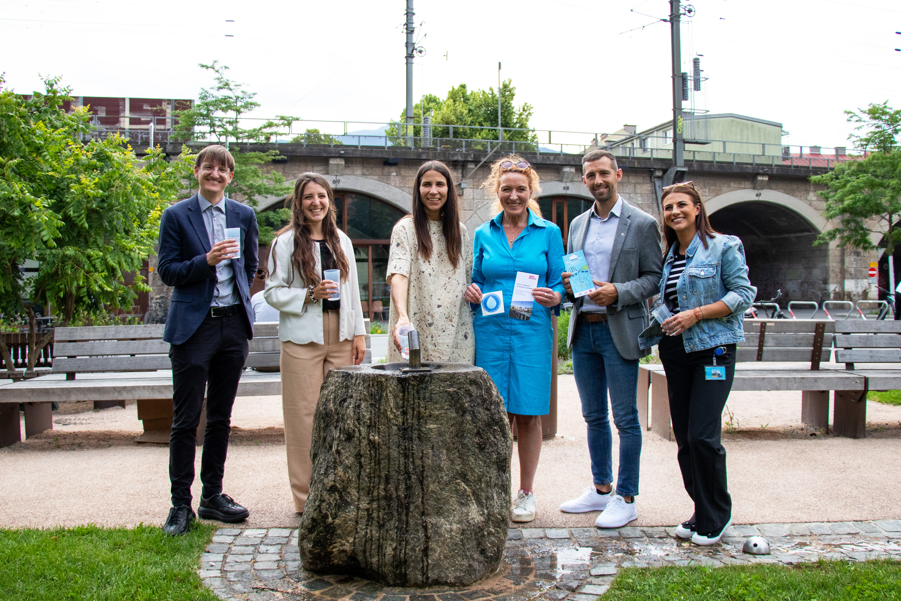 Am heutigen Hitzeaktionstag wurden die ersten Maßnahmen des Hitzeaktionsplans vorgestellt: die Mehrwegbecher der Innsbrucker Kommunalbetriebe AG (IKB) kamen bereits am Bogenfest zum Einsatz, neben jenem im Messepark finden sich 16 weitere öffentliche Trinkbrunnen im Mapping des Landes Tirol. Im Bild v.l.n.r.: Amtsleiter Michael Deflorian, Sarah Rasi (BürgerInnenbeteiligung und partizipative Stadtgestaltung), Stadträtin Janine Bex, Christine Schermer (Referat Stadtklima und Umwelt), Christoph Stauder (Land Tirol) und Juliane Humer (tirol kliniken).