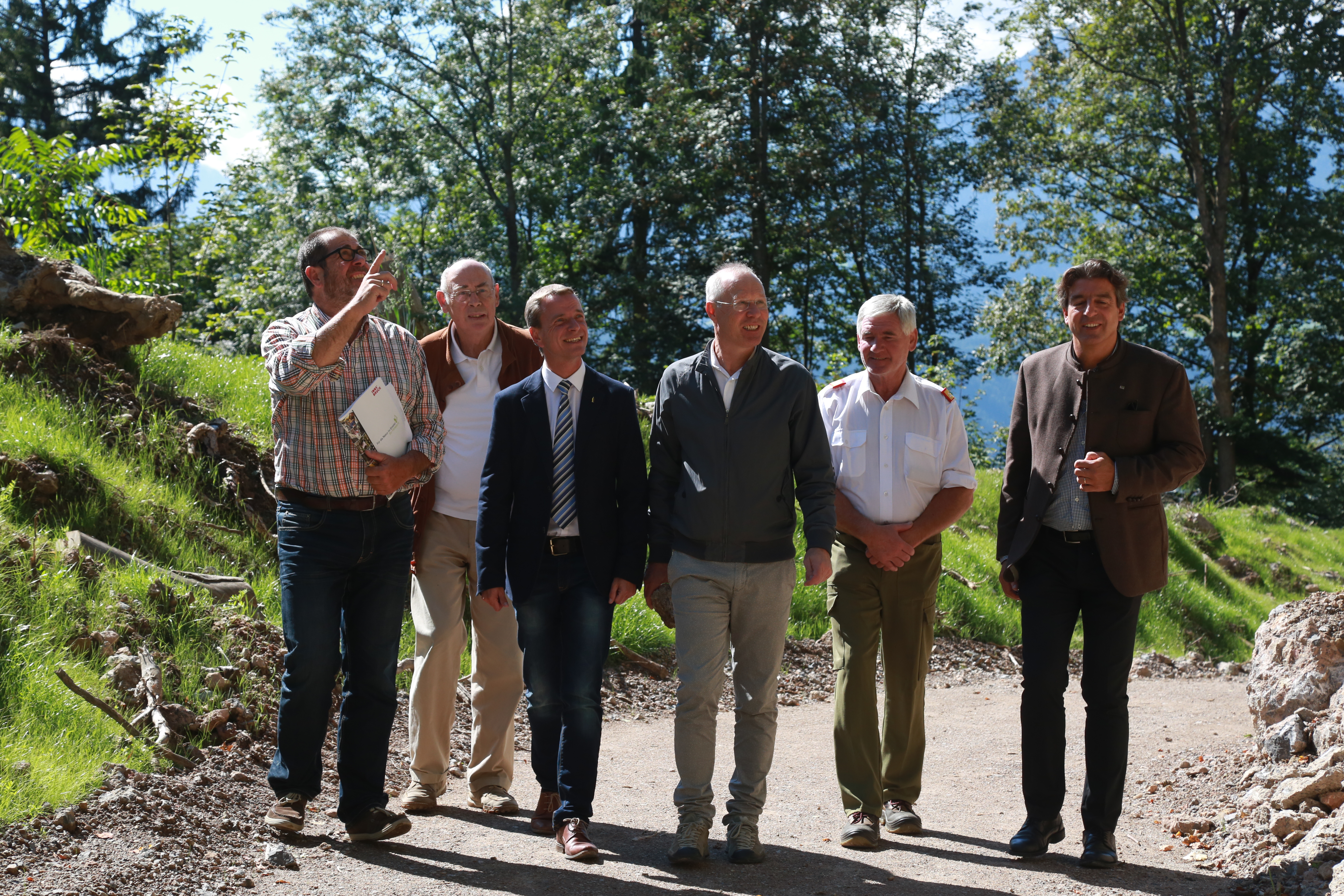 Forstamtsleiter Andreas Wildauer (l.) erläutert die Steinschlagschutzmaßnahmen oberhalb des beliebten und stark frequentierten Wilhelm-Greil-Weges, der mittels Stein-Auffangbereich und errichteten Dämmen (links im Bild) die Sicherheit der WanderInnen gewährleistet (v.l.): Hermann Hell (Innsbrucker Verschönerungsverein), Vizebürgermeister Christoph Kaufmann, Andreas Rauch (Naturstrom Mühlau), Walter Laimgruber (Bezirksfeuerwehrkommandant) und Markus Lutz (IKB).
