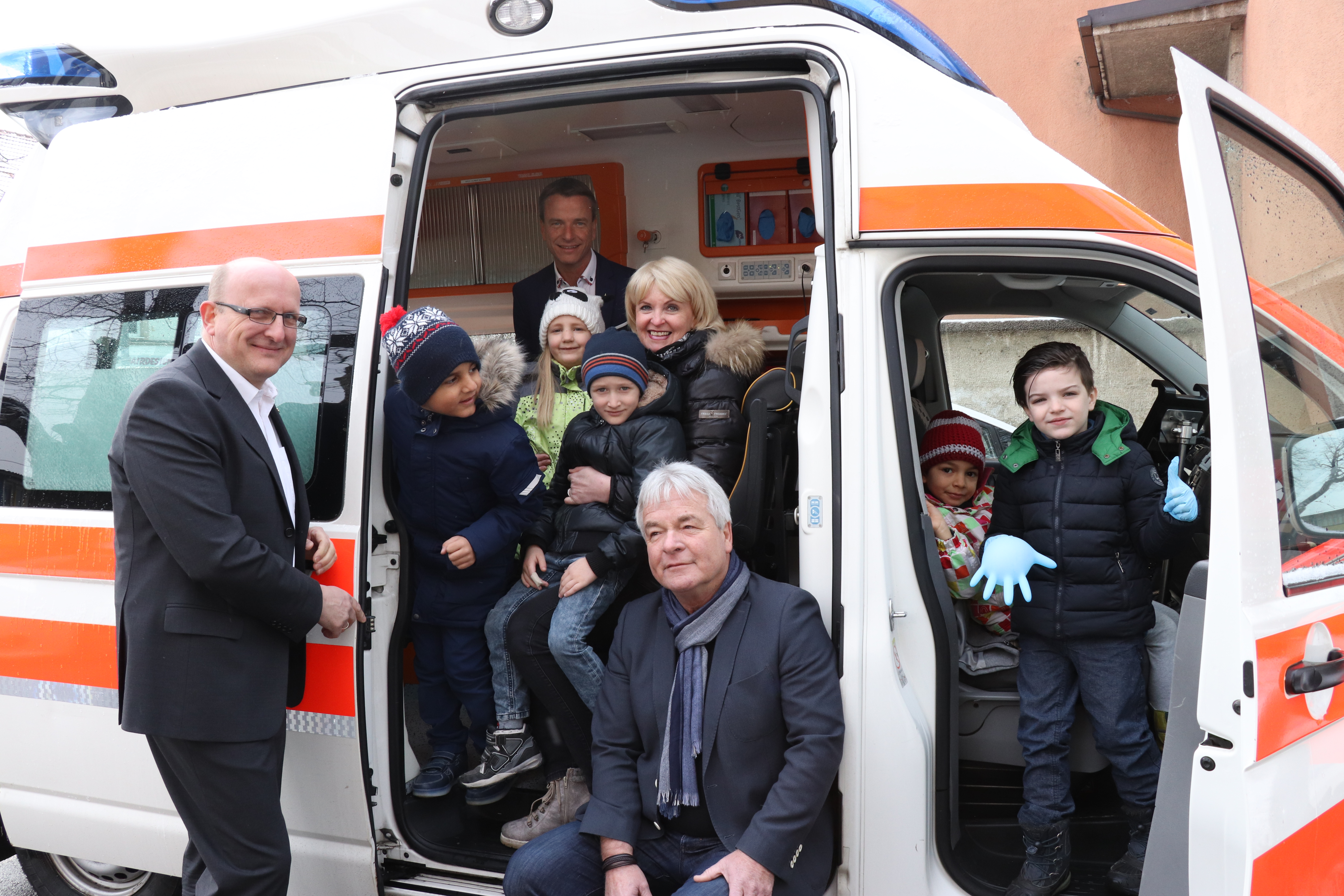 Inspezierten gemeinsam mit den Kindern des KG Pradl den Einsatzwagen: Franz Bittersam (GF Johanniter Tirol, l.), Vizebürgermeister Christoph Kaufmann (hinten), KG-Leiterin Elisabeth Siller (KG Pradl) und Bildungsstadtrat Ernst Pechlaner (vorne)